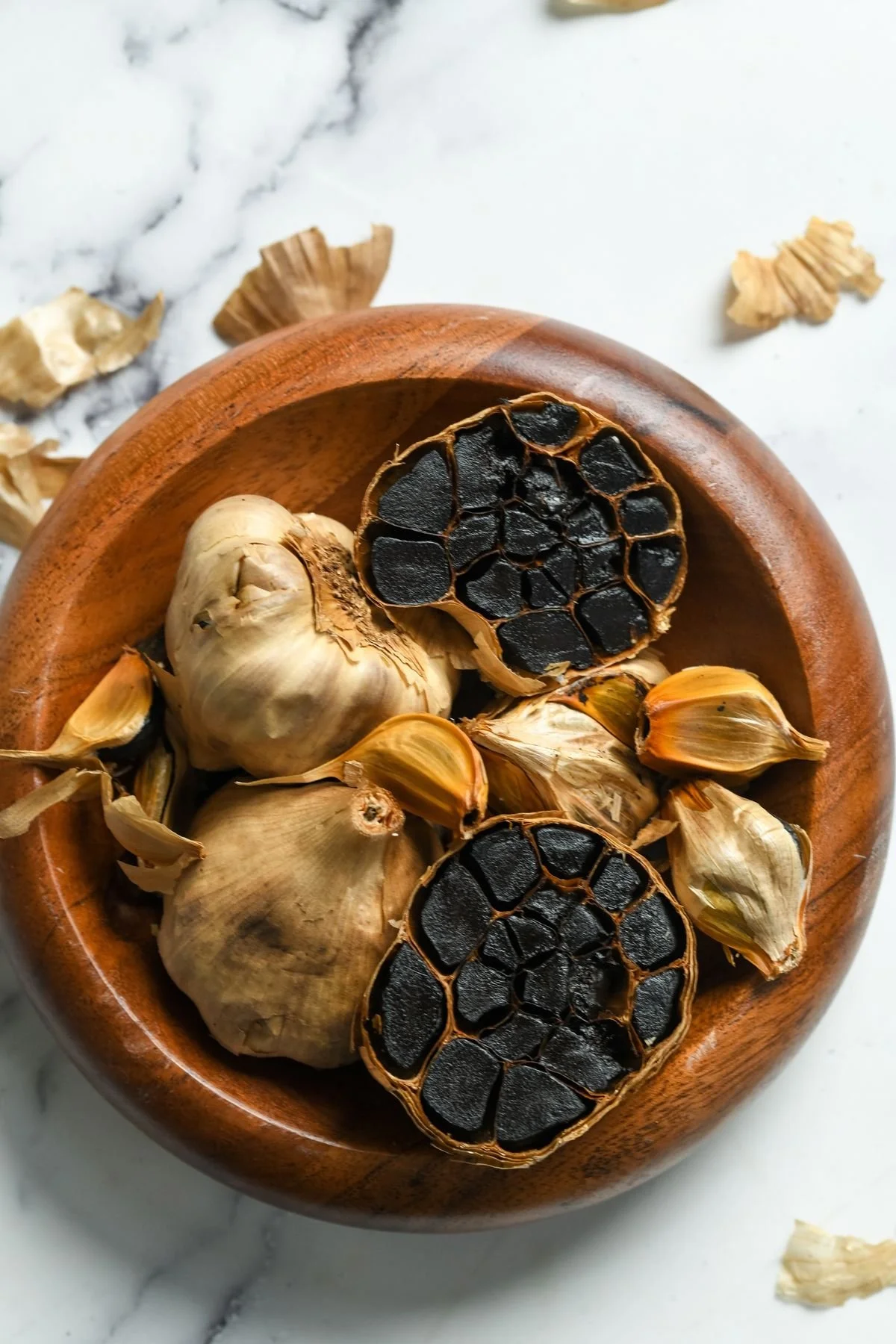 Black garlic bulbs in a wooden bowl